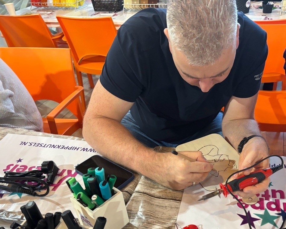 Mannelijke collega volgt een creatieve workshop op een bedrijfsfeest, verzorgd door HIppe Knutsels op locatie